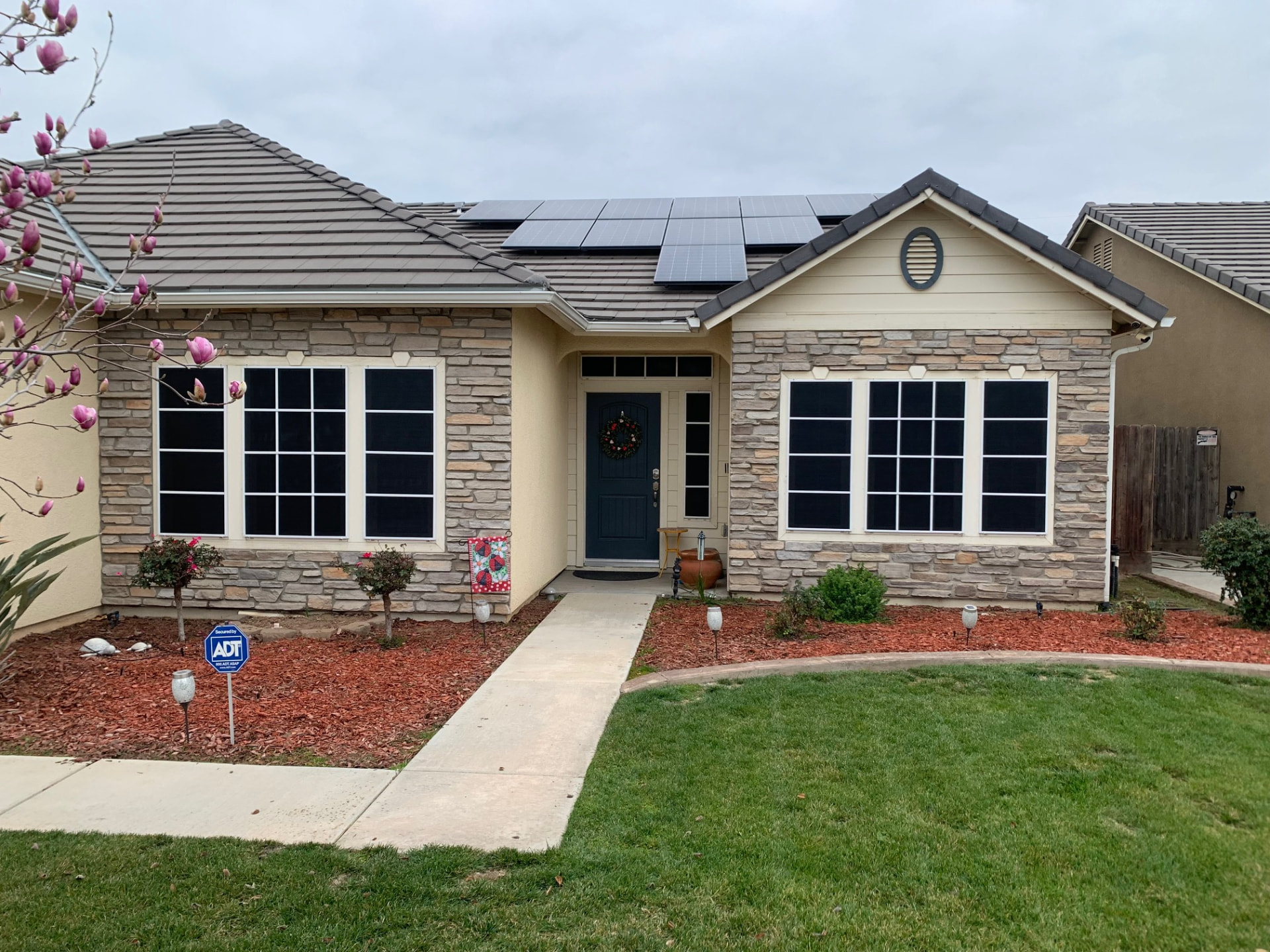 Stone and stucco home with black solar sunscreens on every front window